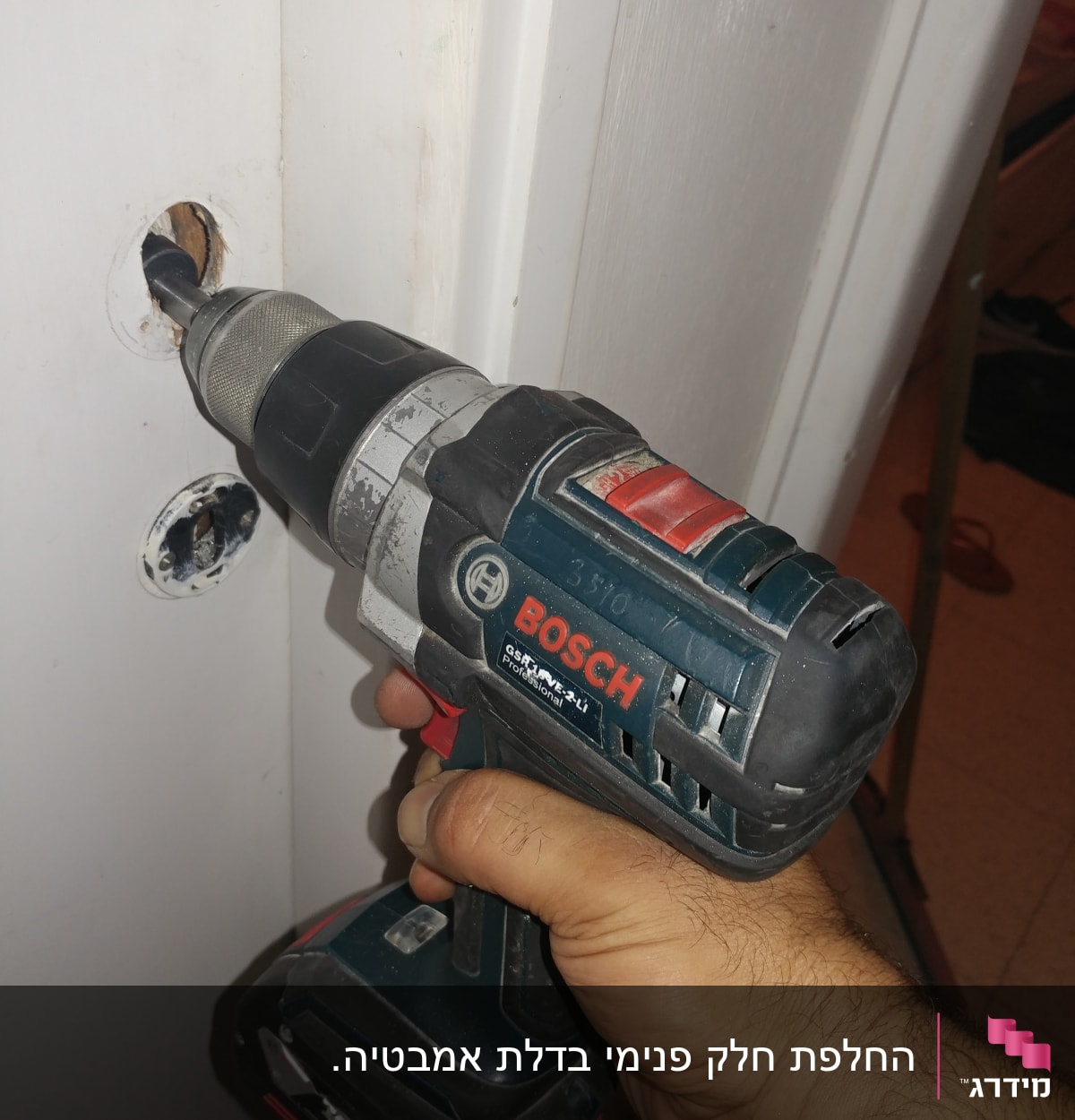 יד מחזיקה מקדחה חשמלית קודחת בדלת עץ